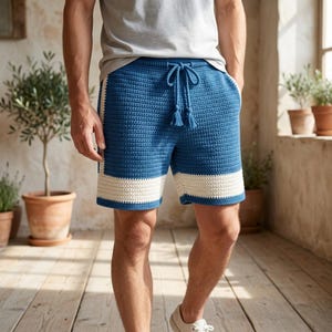 May include: Blue crochet shorts with white trim and a drawstring waist. The shorts have a textured appearance and a relaxed fit. The shorts are knee-length and have a casual style.