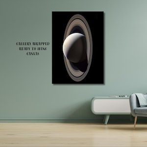 May include: A rectangular gallery wrapped canvas print featuring a vertical depiction of the planet Saturn with its prominent rings against a solid black background. The text "GALLERY WRAPPED READY TO HANG CANVAS" is printed in black on the left side.