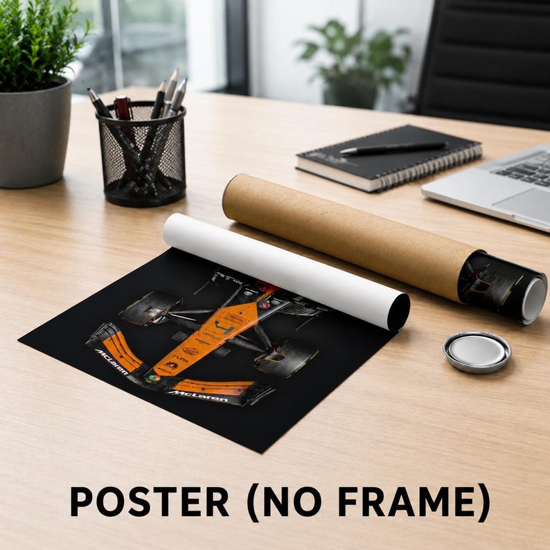 May include: A rectangular poster featuring a top-down view of a McLaren Formula 1 race car in its signature orange and black livery. The poster is shown partially unrolled next to a brown cardboard shipping tube on a wooden desk surface.