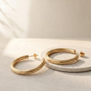 May include: A pair of gold hoop earrings featuring a twisted, spiraled metal texture. Each earring is circular in shape with a polished finish and includes a standard post and butterfly back closure for secure attachment to the earlobe.