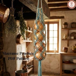 May include: A hanging macrame produce holder crafted from light blue and cream-coloured cord, featuring a knotted net design that contains four round yellow onions. The structure ends in a long, decorative tassel at the bottom. Text reads: Macrame Produce PDF Pattern.