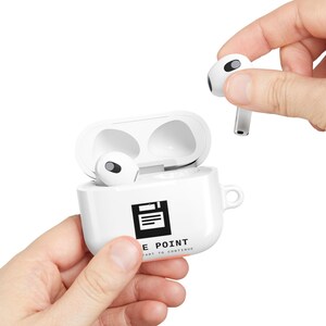 Peut inclure: Un boîtier de charge blanc pour écouteurs sans fil avec une icône de disquette noire et le texte "SAVE POINT" et "PRESS START TO CONTINUE" imprimé sur le devant. Un écouteur blanc est dans le boîtier et un autre est tenu au-dessus.
