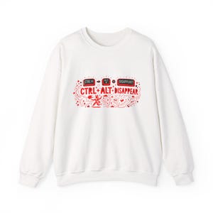 Puede incluir: Sudadera blanca de cuello redondo con un gráfico rojo. El gráfico presenta el texto "CTRL + ALT + DISAPPEAR" en una fuente estilizada, junto con elementos decorativos. La sudadera tiene mangas largas y un diseño clásico e informal.