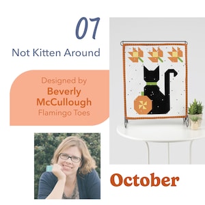 May include: A small, framed quilt featuring a black cat with a green collar and a pumpkin. The quilt has a white background with black dots and orange and yellow floral accents. The text "Not Kitten Around" and "October" are also visible.