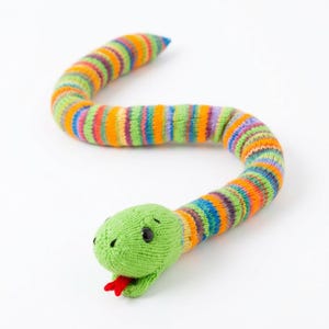 May include: A knitted snake toy in a curved S-shape. The body is striped with green, orange, blue, and purple. The head is green with black eyes and a red tongue. The toy is made of soft yarn.