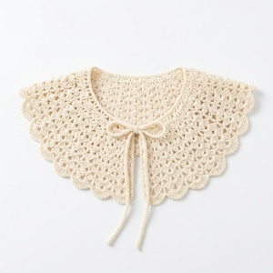 Puede incluir: Cuello de crochet color crema con borde festoneado y cierre de lazo. El diseño calado del cuello añade un toque de encanto vintage. Este accesorio hecho a mano es perfecto para añadir un toque único a cualquier atuendo.