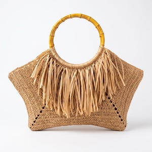 May include: A star-shaped woven straw handbag in a natural tan color. The bag features a circular bamboo handle and a decorative fringe made of thin, light beige paper-like strips attached to the top section of the bag's front surface.