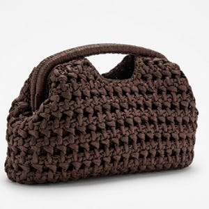Puede incluir: Un bolso de mano marrón tejido con un asa superior redondeada. El bolso está hecho de un material grueso y texturizado con un patrón repetitivo. El asa es de un tono marrón más oscuro que el cuerpo del bolso. El bolso tiene una forma estructurada y parece estar vacío.
