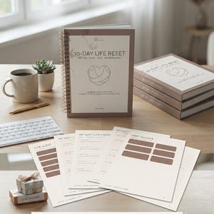 Puede incluir: Una agenda de espiral 30-Day Life Reset con cubierta beige, un icono de coraz&oacute;n y texto. El conjunto incluye hojas sueltas tituladas Life Audit, My Soft-Life Vision y Habit Builder, junto a una pila de tres agendas id&eacute;nticas.