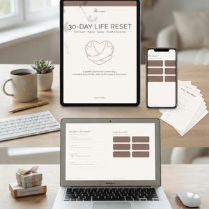 Puede incluir: Un planificador digital 30-Day Life Reset mostrado en una tableta, un tel&eacute;fono inteligente y una pantalla de port&aacute;til. La interfaz presenta un icono de coraz&oacute;n y texto que incluye Self-Care, Habits, Goals, Mindful Routines y My Soft-Life Vision.