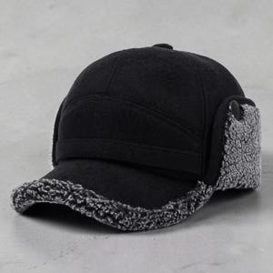 May include: A black baseball cap featuring a textured, grey, fleece-like lining on the underside of the brim and on the ear flaps. The cap has a structured crown with a horizontal band across the front and a small black button on the side flaps.
