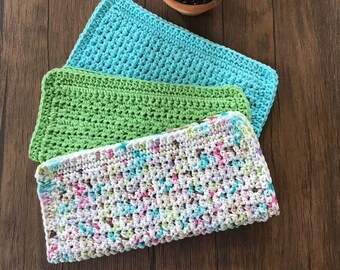 May include: Three crocheted dishcloths in different colours and patterns. The top dishcloth is light blue, the middle dishcloth is green, and the bottom dishcloth is white with multi-coloured flecks.