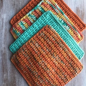 May include: Four crocheted dishcloths in a stack. The top dishcloth is teal green, the next two are orange and yellow striped, and the bottom dishcloth is a mix of orange, yellow, and green.