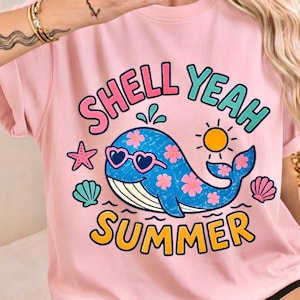 May include: A pink t-shirt with a graphic of a blue whale wearing heart-shaped sunglasses and pink flowers. The text "SHELL YEAH SUMMER" is displayed in colourful lettering, with a starfish, sun, and seashells.