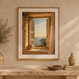 Könnte beinhalten: Ein gerahmter Wandkunstdruck, der ein offenes Fenster mit Holzläden und Blick auf eine Küste bei Sonnenuntergang zeigt. Die Szene umfasst einen Steinsims, eine kleine Keramikvase und weiches Licht, das durch Vorhänge einfällt.
