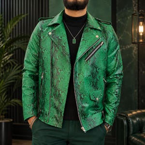 Peut inclure: Une veste de moto vert vif avec un motif peau de serpent noir, des fermetures éclair en métal argenté, un large revers cranté, des épaulettes et une petite poche à rabat sur le devant. La veste est portée sur un pull à col roulé noir.