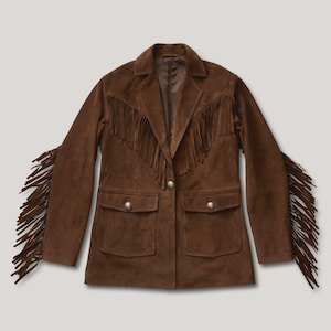 May include: A brown suede jacket featuring long fringe detailing along the sleeves and across the chest. The jacket includes a collared neckline, a single front button closure, and two front flap pockets, each secured with a metallic button.