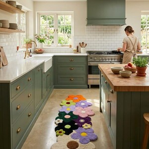 May include: A runner rug featuring a series of interconnected, multi-colored flower shapes in shades of orange, lime green, lavender, pink, dark green, black, and cream, each with a contrasting center, laid out on a kitchen floor.