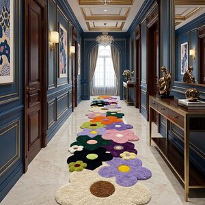 May include: A long runner rug featuring a repeating pattern of large, multi-colored flower shapes in shades of cream, purple, green, black, orange, and pink, laid out on a light-colored marble floor in a hallway with blue paneled walls.