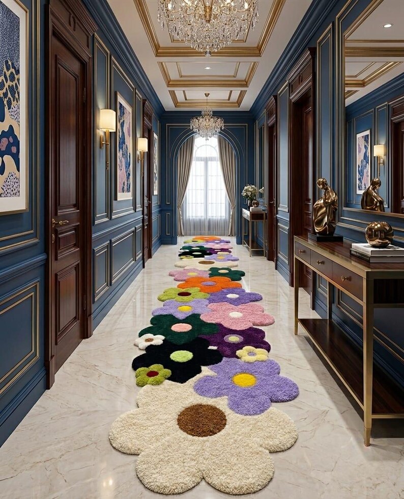 May include: A long runner rug featuring a repeating pattern of large, multi-colored flower shapes in shades of cream, purple, green, black, orange, and pink, laid out on a light-colored marble floor in a hallway with blue paneled walls.