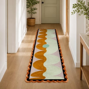 Peut inclure: Un long tapis de couloir rectangulaire avec un bord festonné et un motif de vagues répétitif dans des tons jaune moutarde, vert menthe pâle et lavande doux. Le tapis est bordé d'une ligne noire épaisse et d'une bordure orange festonnée.
