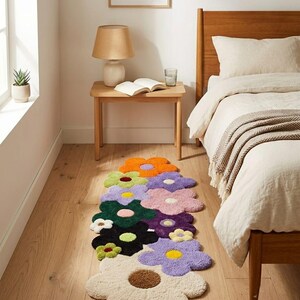 May include: A runner rug featuring a cluster of tufted flowers in various colors including orange, light green, lavender, dark green, pink, purple, black, and cream. Each flower has a contrasting center, creating a vibrant, multi-colored floral pattern.