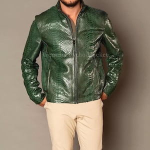 Könnte beinhalten: Eine dunkelgrüne Jacke mit strukturiertem Schlangenledermuster, hohem Kragen, durchgehendem Frontreißverschluss und langen Ärmeln. Die Jacke hat eine glänzende Oberfläche und wird mit einer hellbeigen Hose kombiniert. Der Text Genuine Python Jacket ist sichtbar.