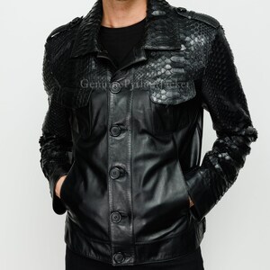 May include: A black jacket featuring a combination of smooth leather and textured snakeskin panels on the shoulders, collar, and sleeves. The garment includes a button-down front closure, two chest pockets with flaps, and a black shirt underneath.