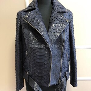May include: A dark blue motorcycle jacket crafted from textured snakeskin leather. The jacket features a wide notched collar, an asymmetrical silver-tone metal zip closure, zipped side pockets, and a matching belt with a metal buckle.
