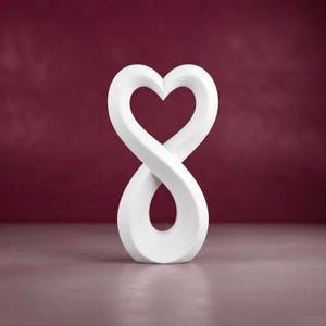 Könnte beinhalten: Eine glatte, mattweiße Skulptur mit einer durchgehenden, fließenden Form, die ein Unendlichkeitssymbol an der Basis mit einer Herzform an der Spitze kombiniert. Das Objekt ist einfarbig weiß mit geschwungenen Kanten und symmetrischem Design.