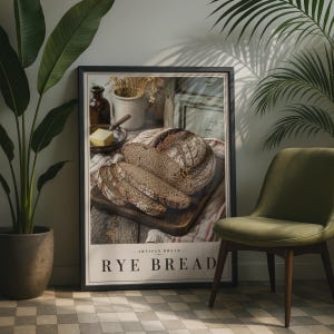 May include: A framed wall art print featuring a photograph of a sliced loaf of dark rye bread on a wooden cutting board, with a small bowl of butter and a ceramic jar in the background. The text "ARTISAN BREAD" and "RYE BREAD" is printed below.