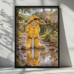 May include: A framed wall art print featuring a frog wearing a yellow raincoat and matching yellow rain boots standing in a muddy puddle. A wooden sign nearby reads BIGGER PUDDLES BRIGHTER DAYS with a heart symbol. A small duck stands in the background.