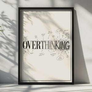May include: A framed wall art print featuring the word OVERTHINKING in black capital letters. The text is surrounded by handwritten notes, arrows, and question marks, with the right side of the word dissolving into a dense, chaotic black scribble.