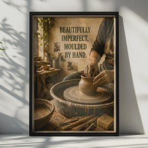 May include: A framed wall art print featuring a potter shaping a clay vessel on a wheel. The text reads, "BEAUTIFULLY IMPERFECT, MOULDED BY HAND." The scene includes pottery tools, a sponge, and a bowl of slip, all rendered in warm, earthy tones.