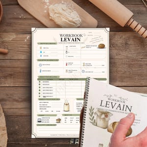 May include: A workbook titled "Workbook Levain" with a spiral binding, featuring a detailed guide to fermentation. The image includes ingredients, a wooden rolling pin, a bowl of flour, and a wooden surface.