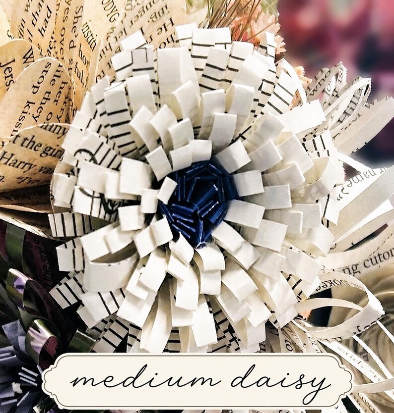 May include: A handcrafted paper flower sculpture featuring layered white strips with black musical staff lines and a dark blue center. The petals are constructed from cut paper, and the base includes a label with the text medium daisy.