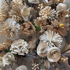 May include: A decorative bouquet of handcrafted flowers made from vintage book pages, featuring various rose and daisy shapes. The arrangement includes dried lavender sprigs, small white baby's breath, and yellow billy ball accents.