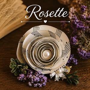 May include: A paper rosette flower crafted from vintage sheet music with black musical notes on off-white paper. The center features a smooth white pearl bead. The flower is accented with small purple dried flowers and green foliage.