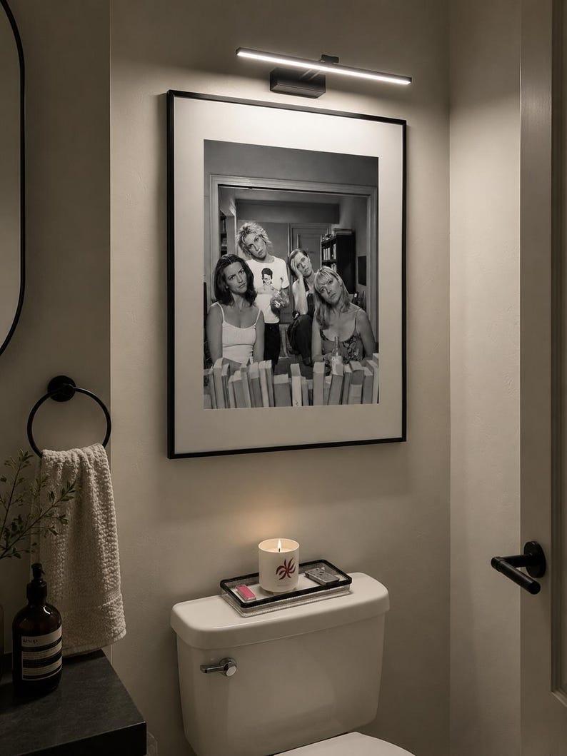 Pu&ograve; includere: Una fotografia incorniciata in bianco e nero che ritrae quattro persone in una stanza, montata su una parete sotto una lampada LED orizzontale. L'immagine mostra un gruppo di persone in un ambiente informale, presentata in una sottile cornice nera con un passe-partout bianco.