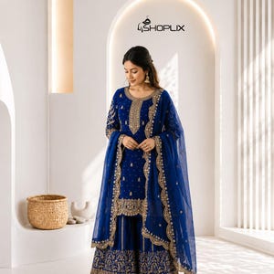 Pode incluir: Um conjunto bordado azul royal com uma túnica de manga comprida, calças de perna larga e um lenço transparente a condizer. A roupa é adornada com bordados dourados intrincados e contas. O logótipo Shoplix é visível no fundo.