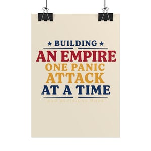May include: A rectangular wall poster with a cream background featuring the text BUILDING AN EMPIRE ONE PANIC ATTACK AT A TIME in distressed blue, red, and yellow lettering, with the smaller text BAD DECISIONS MODE at the bottom.