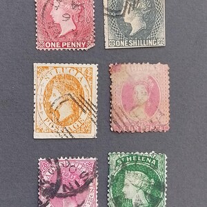 May include: A selection of antique postage stamps, showcasing portraits and text indicating the issuing country and value. The stamps are in shades of pink, green, and orange. The stamps are arranged on a dark grey surface.
