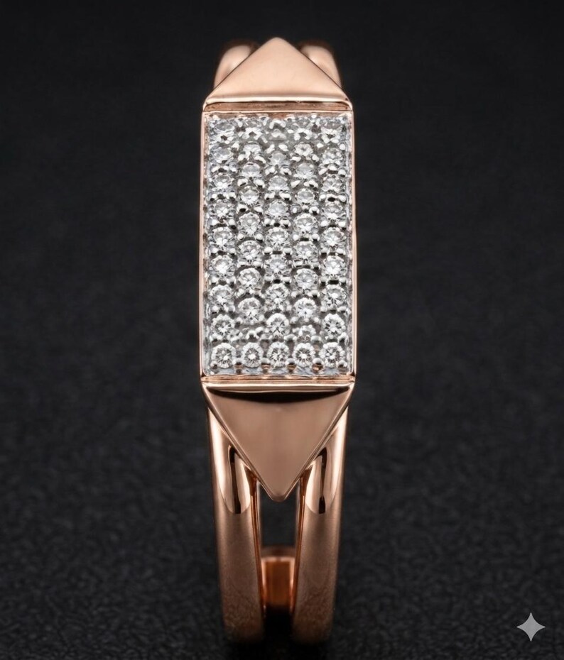 May include: Rose gold ring with a rectangular center filled with small, sparkling white stones. The ring has a geometric design with triangular accents at the top and bottom of the rectangular center. The band is split, creating an open design.