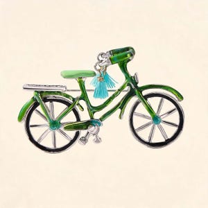 May include: A bicycle-shaped brooch featuring a glossy green enamel finish on the frame, wheels, and handlebars. The seat is a light mint green, and two small, light blue fabric tassels hang from the handlebars. The wheels have silver spokes.