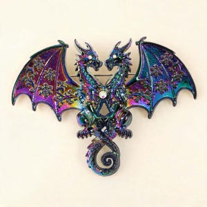 May include: A brooch featuring two iridescent, rainbow-coloured dragons facing each other with their tails intertwined. The dragons have detailed wings with snowflake-like patterns and small clear crystals set into their eyes and centre chest.
