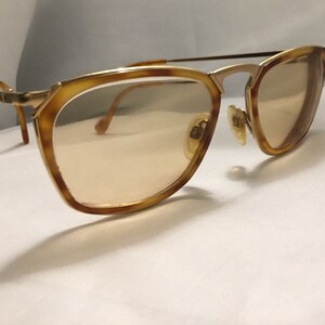 Puede incluir: Gafas de metal dorado con detalles en carey y lentes marrones.