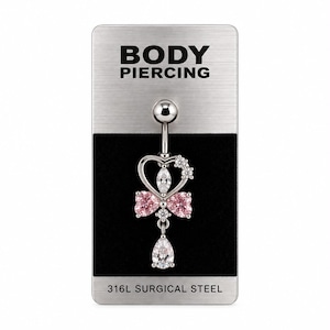 Könnte beinhalten: Ein silberfarbener Bauchnabelpiercing auf einer Anzeigekarte mit der Aufschrift BODY PIERCING und 316L SURGICAL STEEL. Der Schmuck hat einen herzförmigen Rahmen mit zwei rosa herzförmigen Steinen, klaren Marquise- und Rundschliff-Steinen.