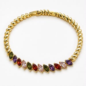 Könnte beinhalten: Ein goldfarbenes Armband mit einer Reihe gedrehter Metallglieder und einem Abschnitt aus marquise-geschliffenen Edelsteinen in verschiedenen Farben wie Rot, Lila, Grün und Hellrosa, befestigt mit einem Metallverschluss auf weißem Grund.