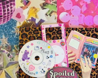 Peut inclure: Un collage avec des CD, un appareil rose Hello Kitty et deux livres "Girl Talk". Les CD sont décorés de cœurs, d'étoiles et des mots "mixtape" et "Play!!". Un autocollant dit "Spoiled Rotten". Le fond présente un imprimé léopard et des paillettes roses.