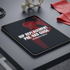 Könnte beinhalten: Ein Tablet mit "HIP REPLACEMENT PRE-HAB GUIDE" und einer roten Hüftillustration. Ein rotes Widerstandsband, ein Knochenmodell und ein schwarzes Kabel liegen auf einer dunklen Oberfläche.